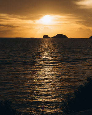 Golden sunset over the ocean with shimmering water reflections, symbolising natural calm and renewal in kluē beauty's wellness rituals