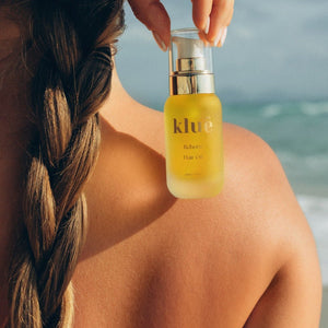 Model applying kluē Reborn Hair Oil – lightweight hair treatment for smoothness